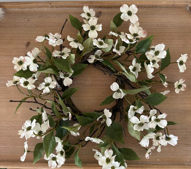 Floral wreath with white flowers and green leaves on a wooden surface