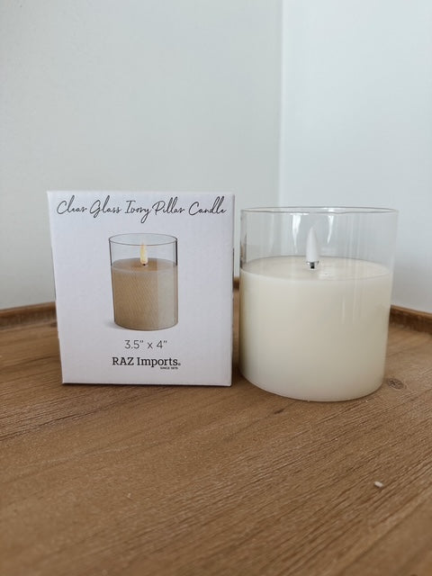 Clear glass ivory pillar candle with packaging on a wooden surface