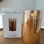 Gold glass candle with packaging on a wooden surface