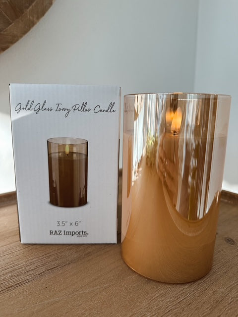 Gold glass candle with packaging on a wooden surface