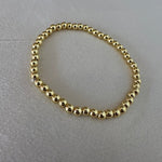 Gold beaded bracelet on a gray surface