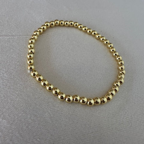 Gold beaded bracelet on a gray surface