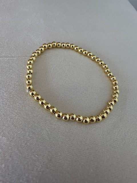 Gold beaded bracelet on a gray surface