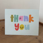 Colorful card with 'Happy' text on a wooden surface