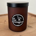 Black container with black lid and 'local farmhouse' label on a wooden surface