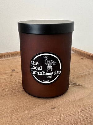 Black container with black lid and 'local farmhouse' label on a wooden surface