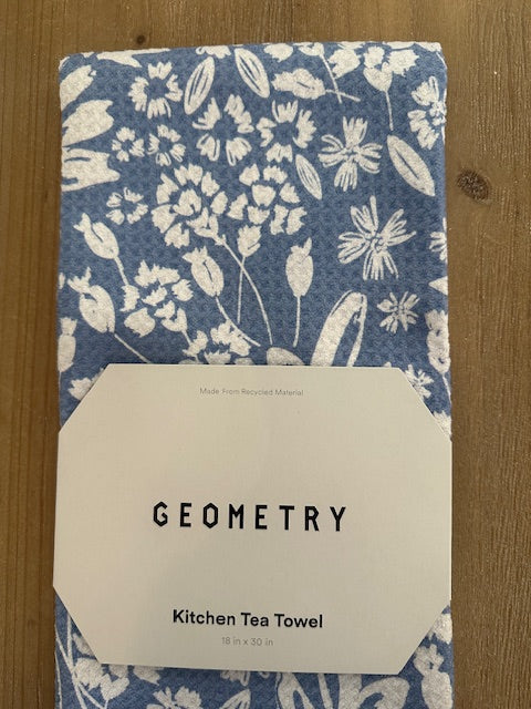 Kitchen tea towel with floral pattern and 'Geometry' label on a wooden surface