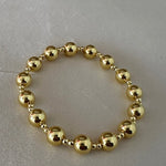 Gold beaded bracelet on a light gray background