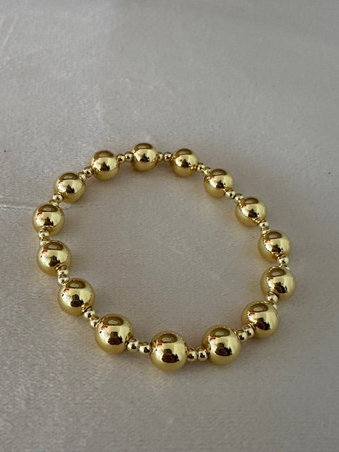 Gold beaded bracelet on a light gray background