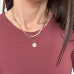 Close-up of a person wearing a necklace with a circular pendant.