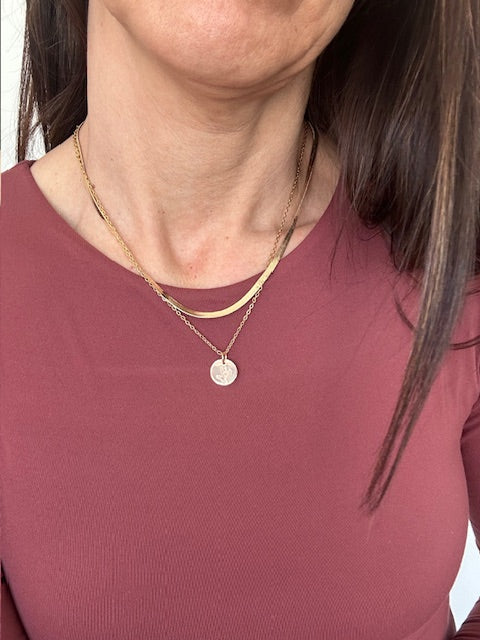Close-up of a person wearing a necklace with a circular pendant.