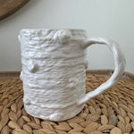 White textured ceramic handbag on a woven surface