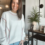 Woman wearing a white sweater with red patterns in a home setting