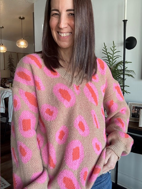 Person wearing a pink and beige patterned sweater indoors.