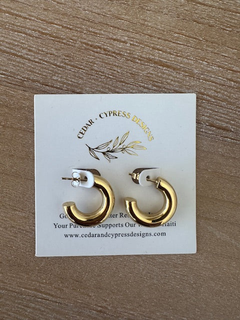 Gold hoop earrings on a Cypress Press Designs card with a wooden background