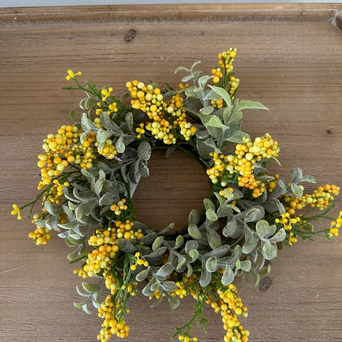 Wreath with yellow berries and green leaves on a wooden door
