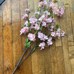 Artificial pink cherry blossom branches on a wooden surface