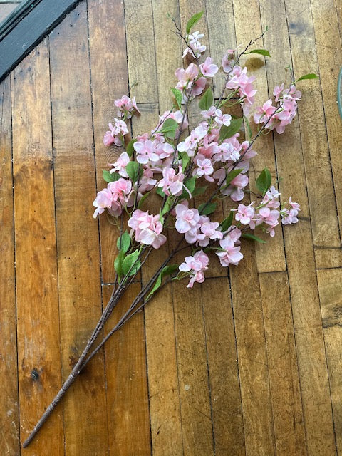 Artificial pink cherry blossom branches on a wooden surface