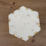 Hexagonal marble coaster with gold accents on a wooden surface