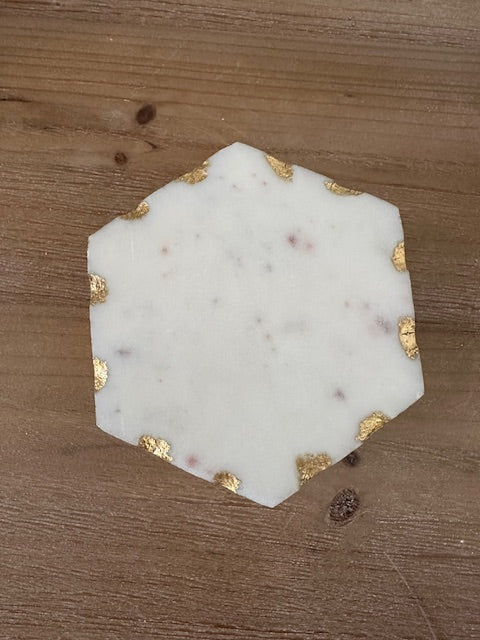 Hexagonal marble coaster with gold accents on a wooden surface