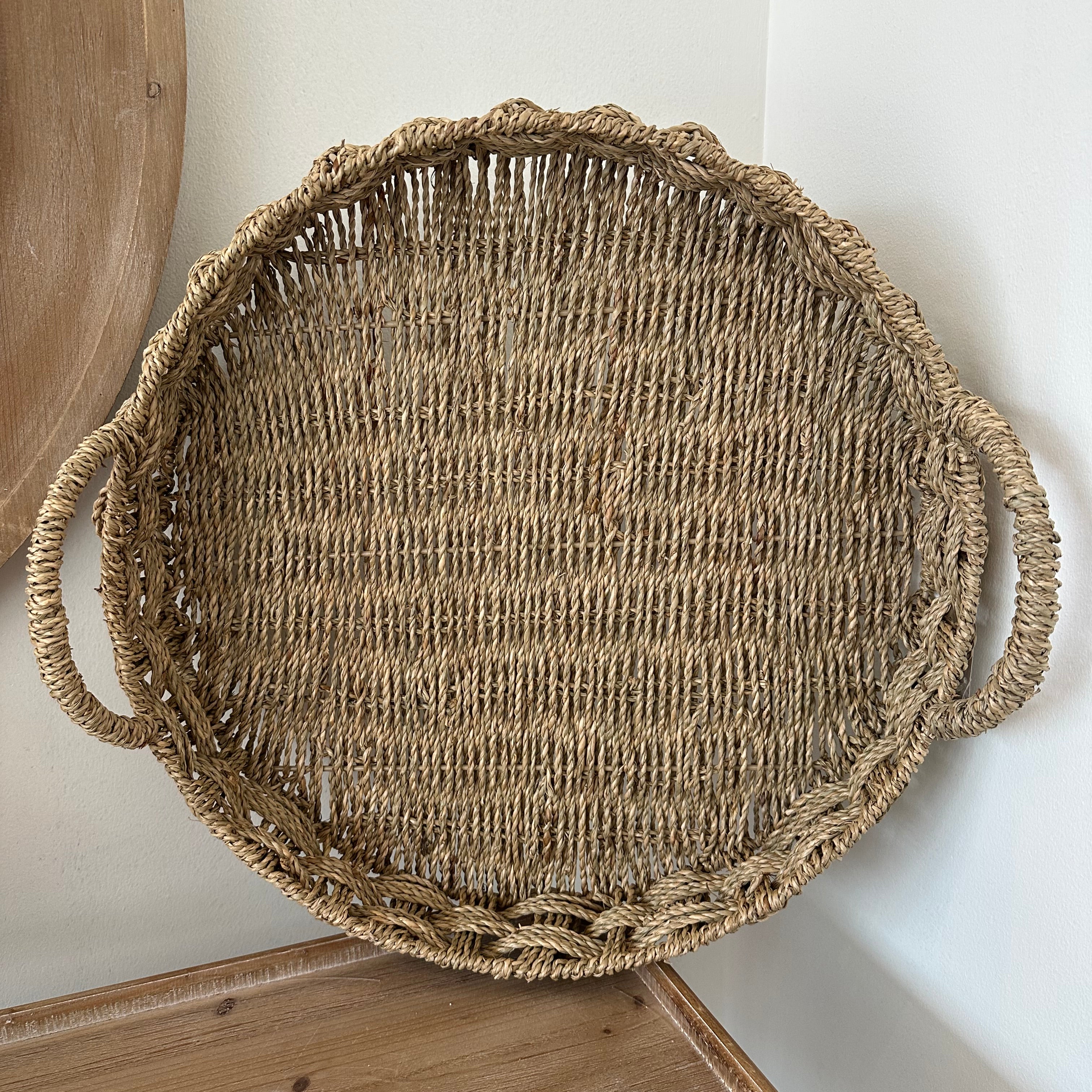 Round woven basket with handles on a light wooden surface