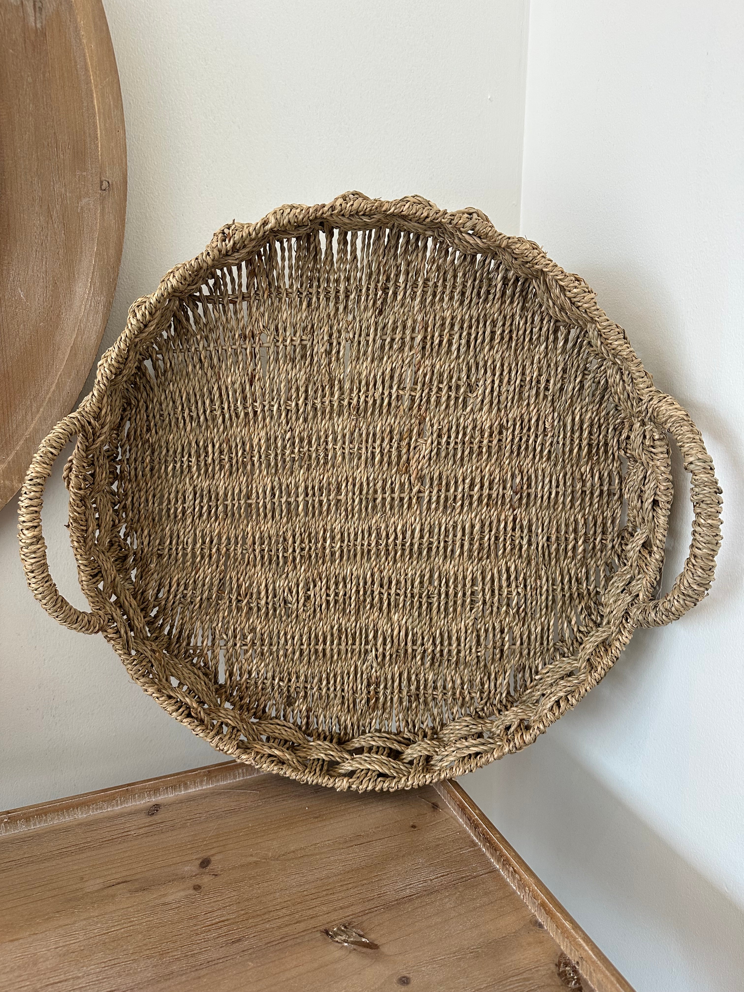 Round woven basket with handles on a light wooden surface