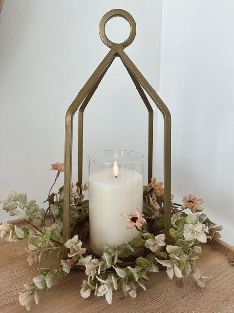 Decorative candle holder with a lit candle and floral elements on a wooden surface.