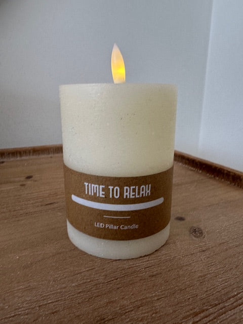 Candle labeled 'Time to Relax' on a wooden surface with a white background
