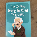 Card with a humorous illustration of an old man and text on a wooden surface