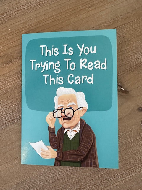 Card with a humorous illustration of an old man and text on a wooden surface