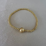 Gold beaded bracelet on a light gray background