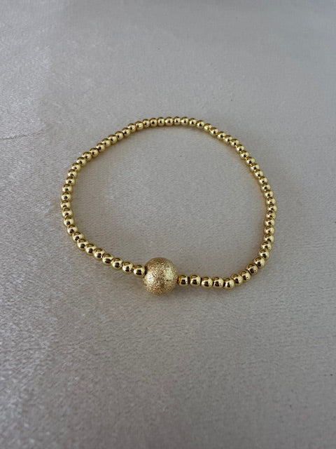 Gold beaded bracelet on a light gray background