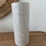 Textured cylindrical object on a wooden surface with a neutral background