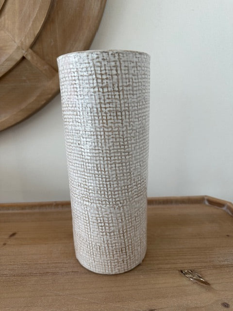 Textured cylindrical object on a wooden surface with a neutral background