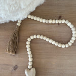Wooden bead garland with tassel on a wooden surface