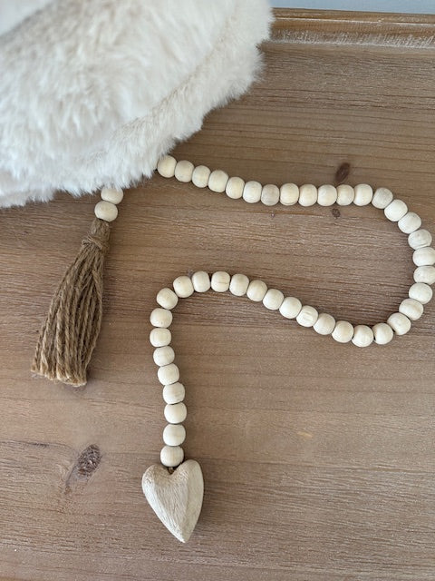 Wooden bead garland with tassel on a wooden surface