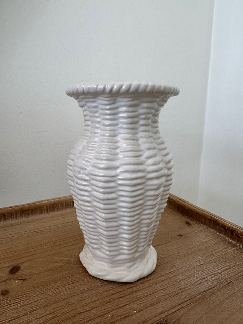 White textured vase on a wooden surface with a white wall background