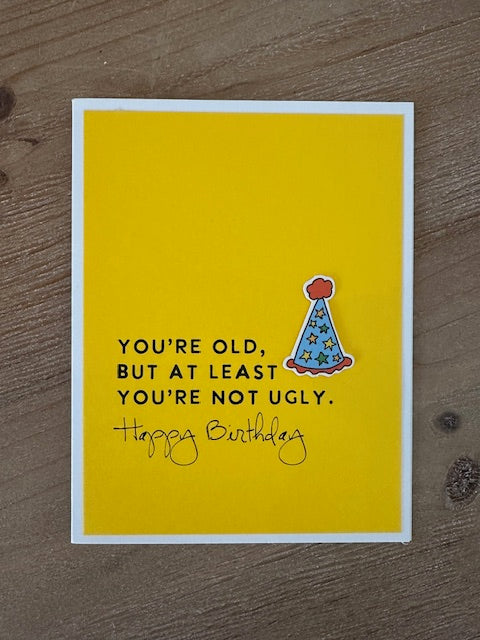 Yellow birthday card with text and a cone illustration on a wooden surface