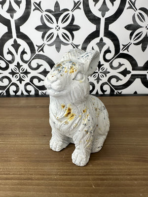 A white concrete rabbit statue with a textured coat and rustic distressed finish, featuring sporadic rusty accents.