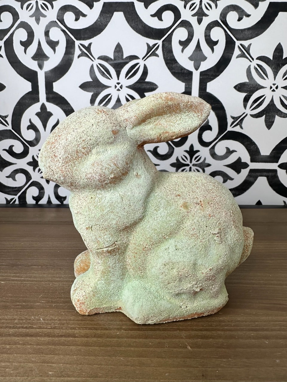 A weathered gray garden rabbit statue with a distressed finish, showing signs of wear.